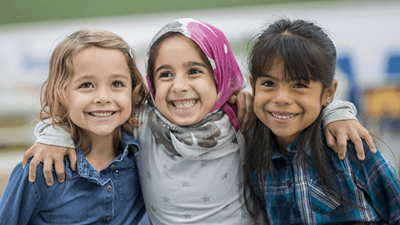 Three girls smiling with their arms around each other