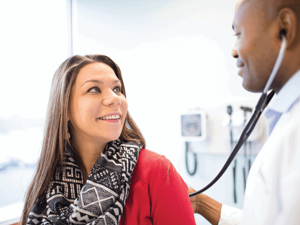 Patient with provider in the exam room, smiling and enjoying her visit.