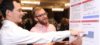 Two male researchers pointing at a research poster